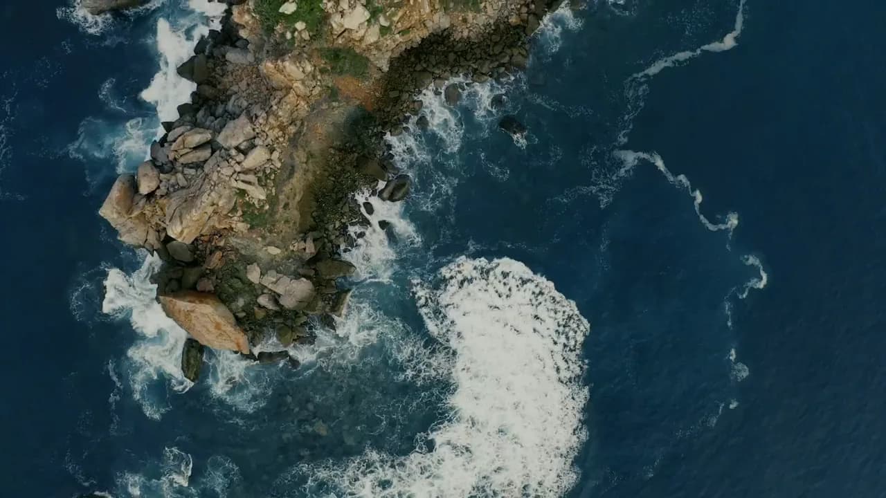 Aerial view of ocean waves breaking around a rocky coast